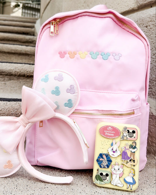 Pink backpack with bow and ears, and a small book or notebook on steps.