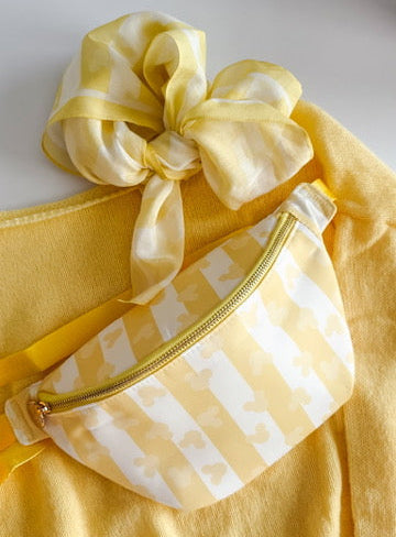 Yellow outfit with a bow and striped pouch on a white background