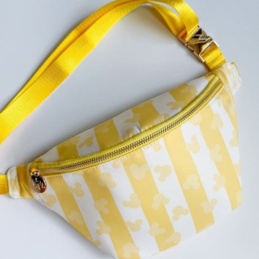 Yellow and white striped fanny pack on a light gray background