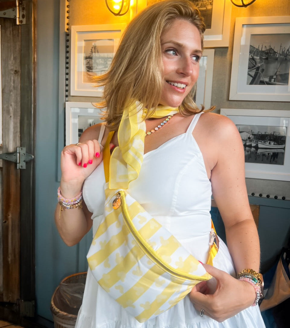 Woman in a white dress with a yellow striped bag in an indoor setting