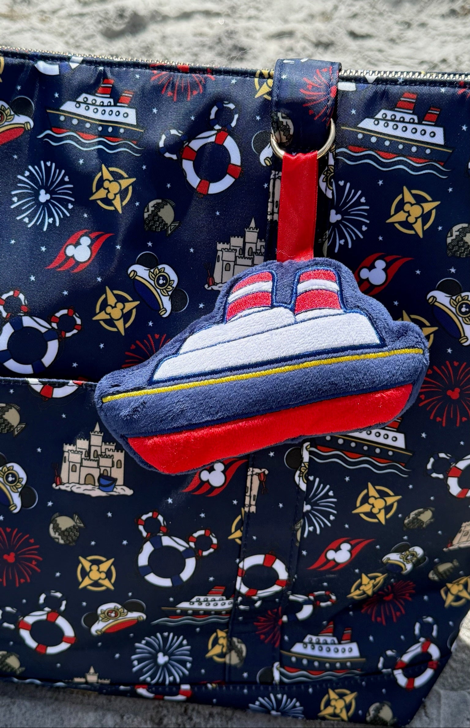 Navy blue bag with maritime-themed design and a ship-shaped plush bag charm.