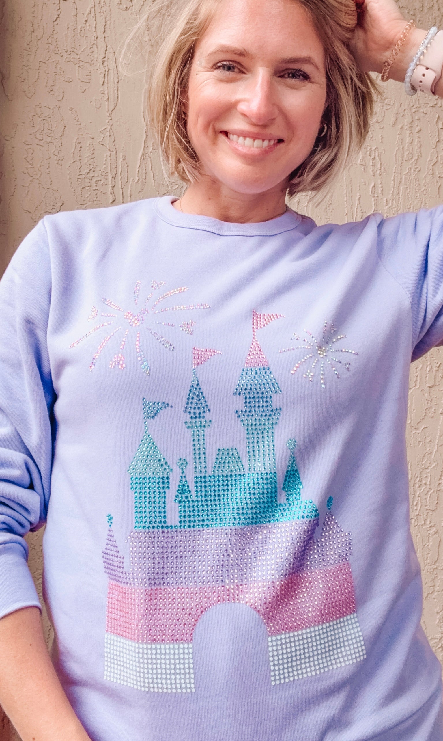 Woman wearing a light purple sweatshirt with a castle design.