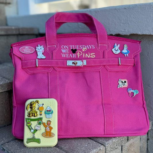 Pink bag with Disney pins on a stone surface