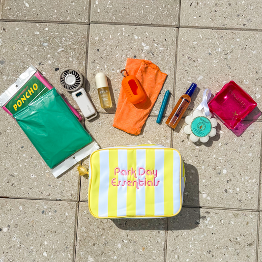 A yellow striped pouch containing ponchos, fan, perfume, cooling towel, reusable straw, sunscreen, and a soap sponge.
