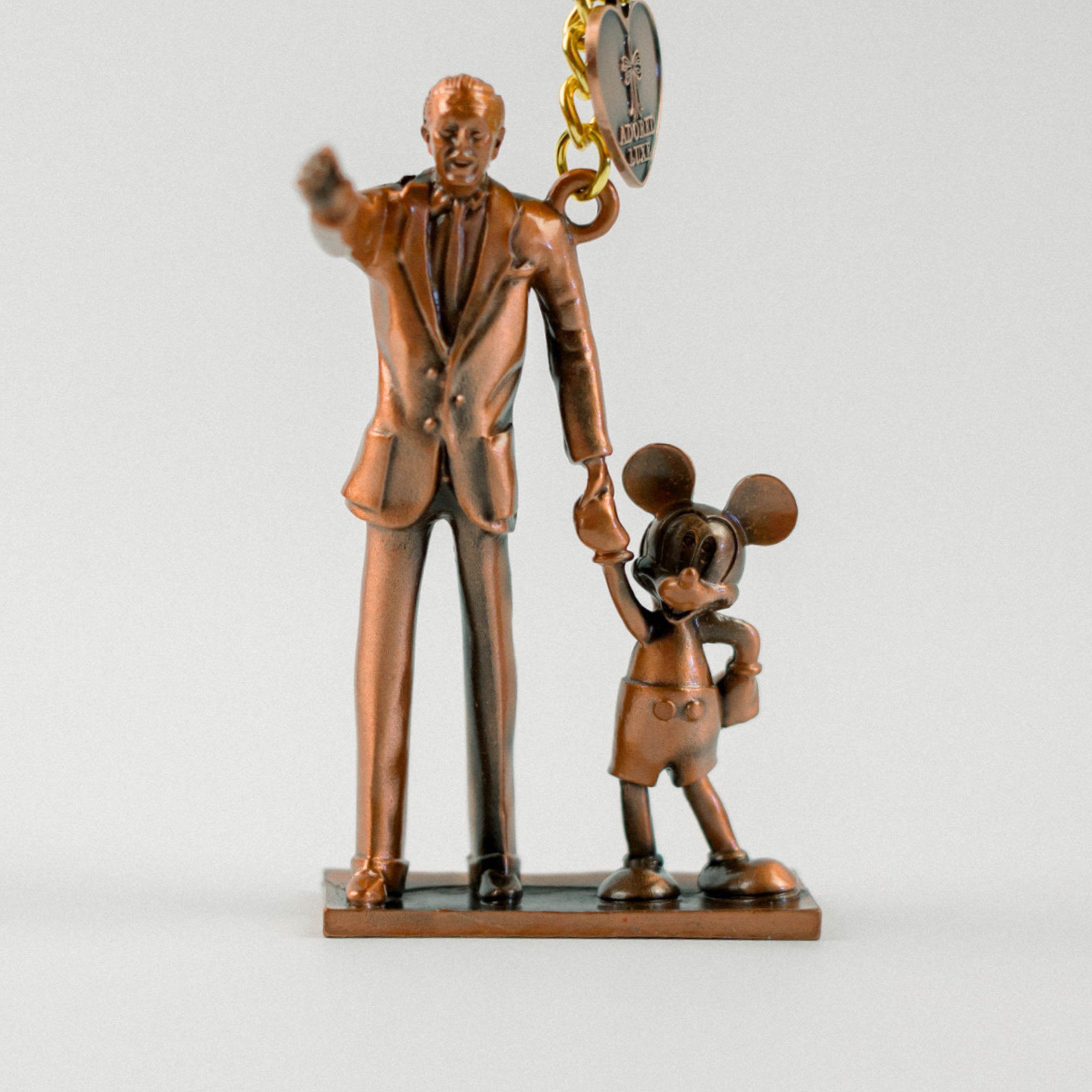 Bronze statue of a man and a mouse figure on a white background
