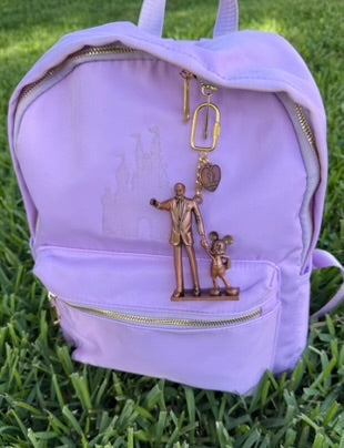 Lavender backpack with decorative charm on grass