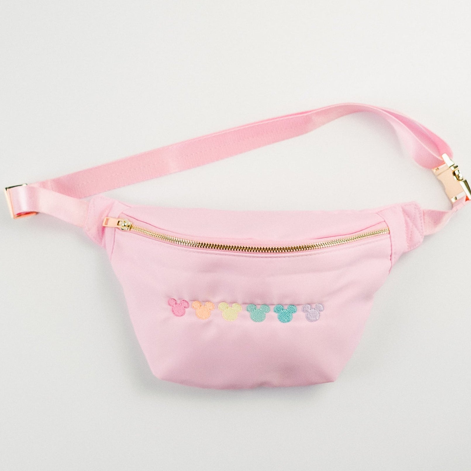 Pink fanny pack with colorful heart designs on a light gray background