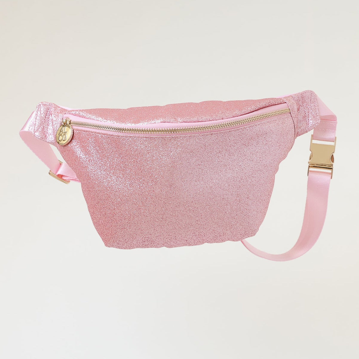 Pink fanny pack with gold zippers on a light gray background