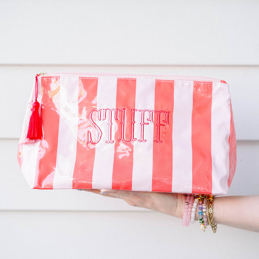 Red and white striped pouch with 'STUFF' text held by a hand against a light wooden background