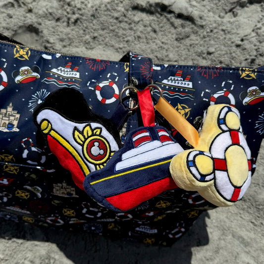 bag with nautical design and plush nautical bag charms on a sand background