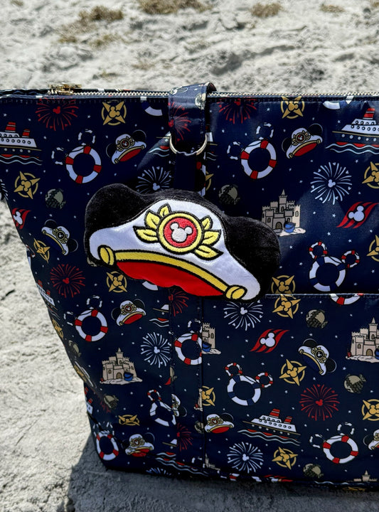 Navy blue bag with maritime pattern and Mouse hat patch on sandy ground